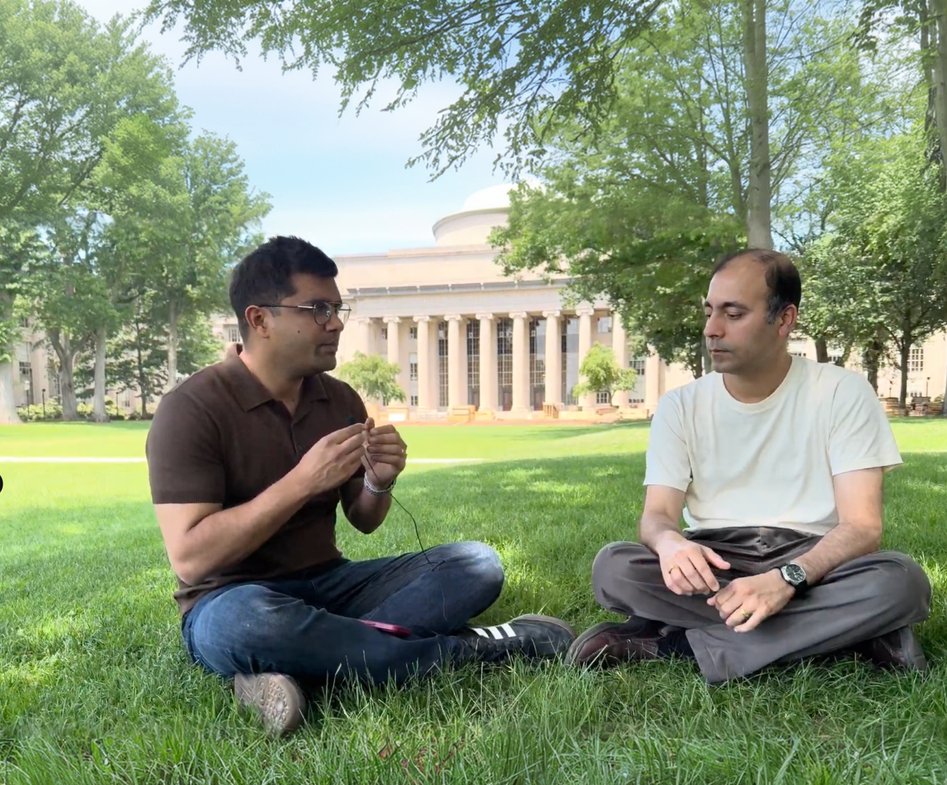 Professor Rohit Karnik and Dhananjay Goel sitting on the grass in front of MIT's Great Dome.